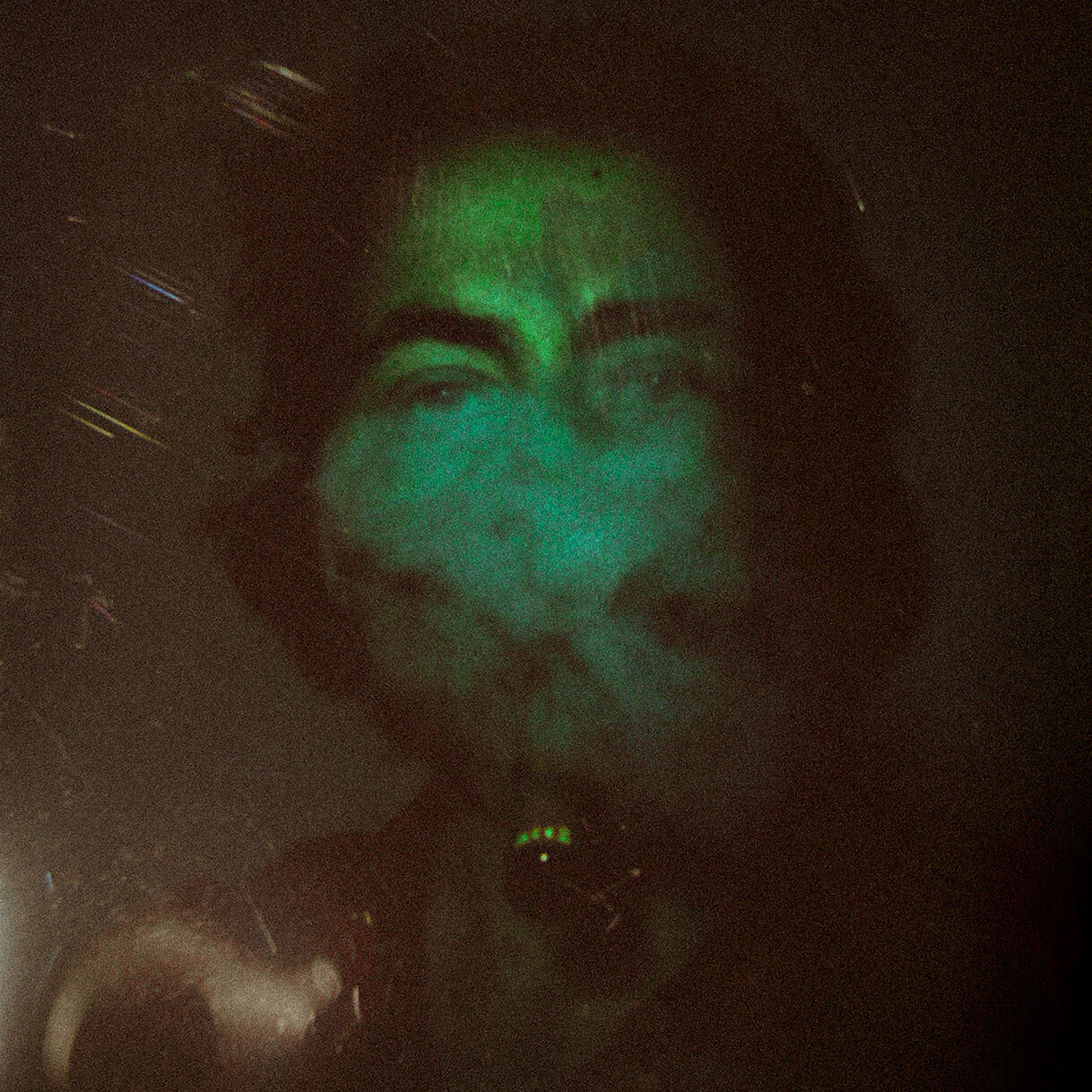 A picture of Mason, a white male, looking at the camera while smoke obscures the bottom half of his face. The entire photo is tinted blue-green.